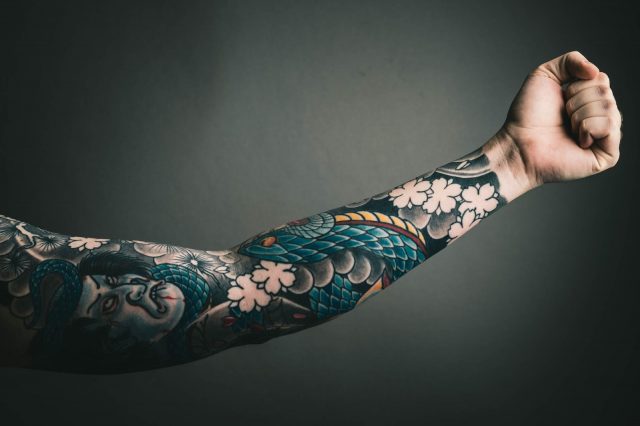 A traditional Japanese irezumi tattoo sleeve featuring intricate designs of dragons, cherry blossoms, and waves.